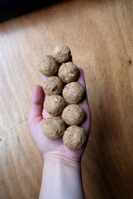 Picture of nine tiny cookies arranged in two rows on a hand over a wooden tabletop.