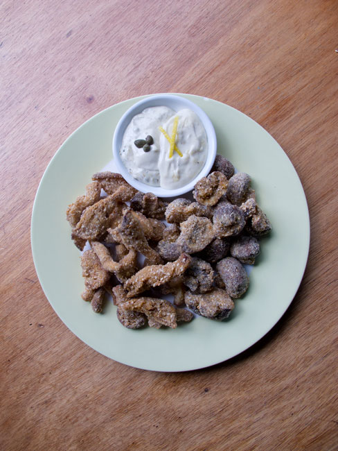 Picture of different fried mushrooms with tartar sauce on a white plate.